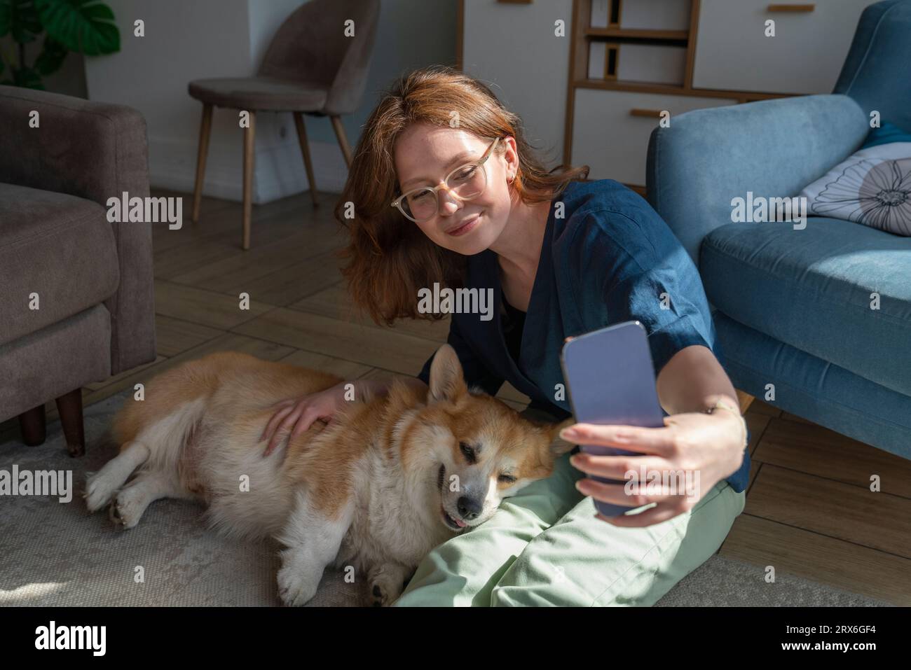Femme prenant selfie avec un chien de compagnie sur un téléphone intelligent à la maison Banque D'Images