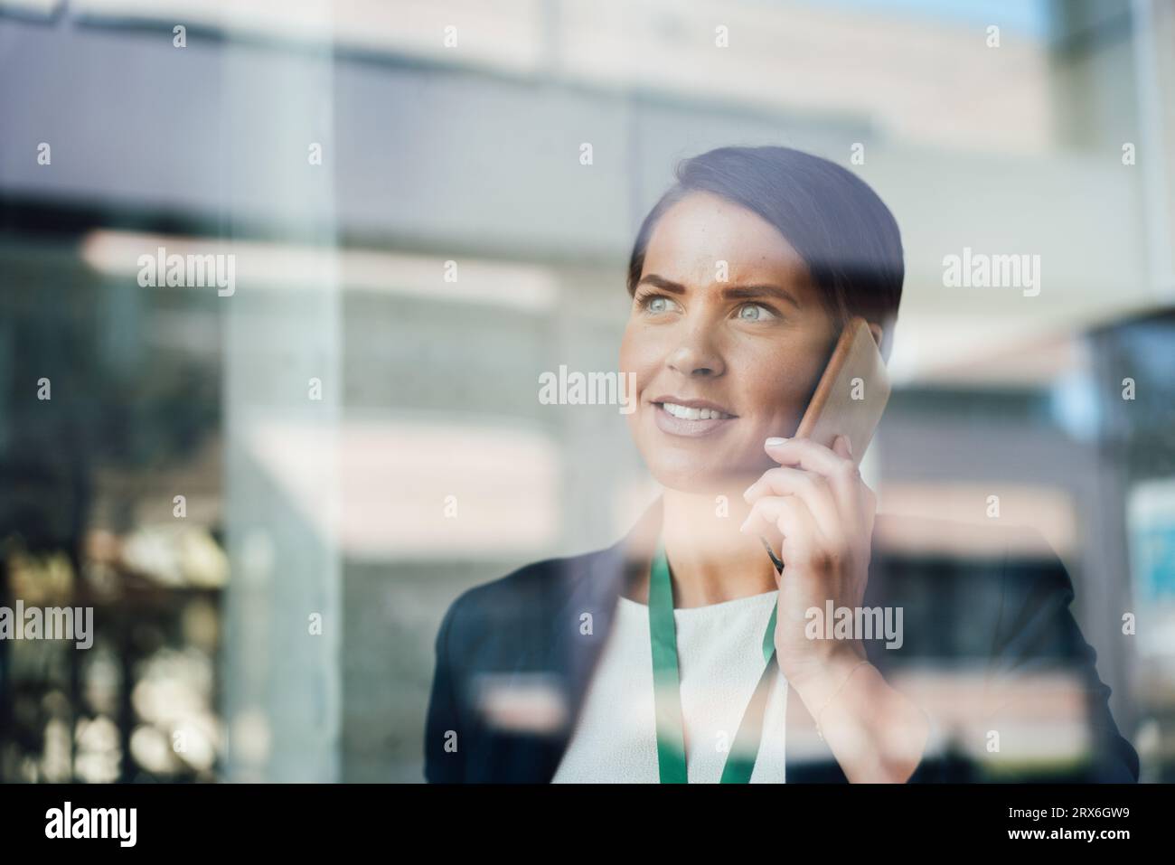 Femme d'affaires parlant sur un téléphone intelligent vu à travers le verre Banque D'Images