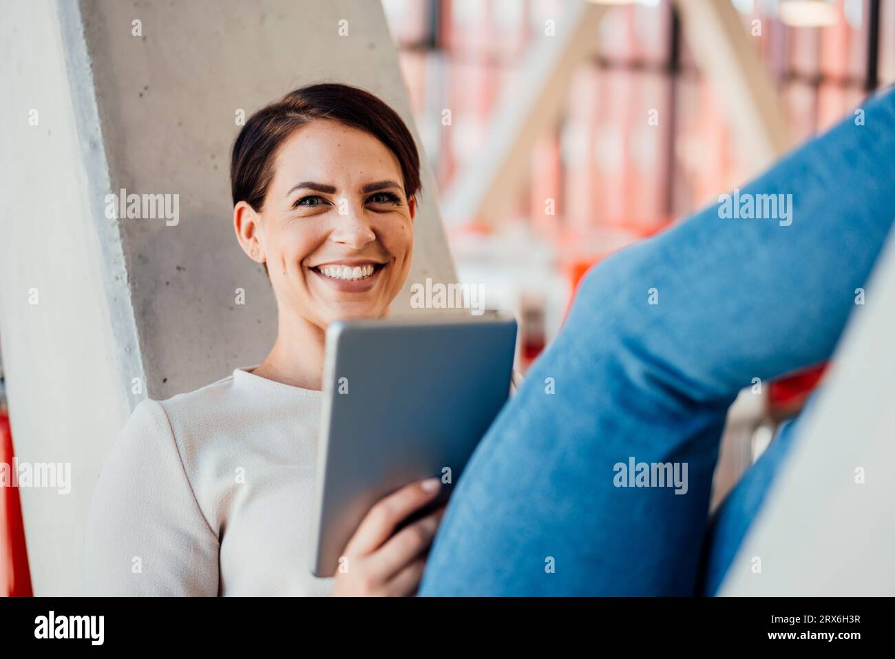 Femme d'affaires heureuse avec tablette PC sur colonne en forme de V. Banque D'Images