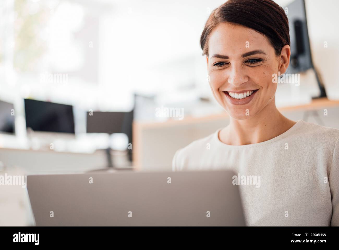 Femme d'affaires souriante utilisant un ordinateur portable au travail Banque D'Images