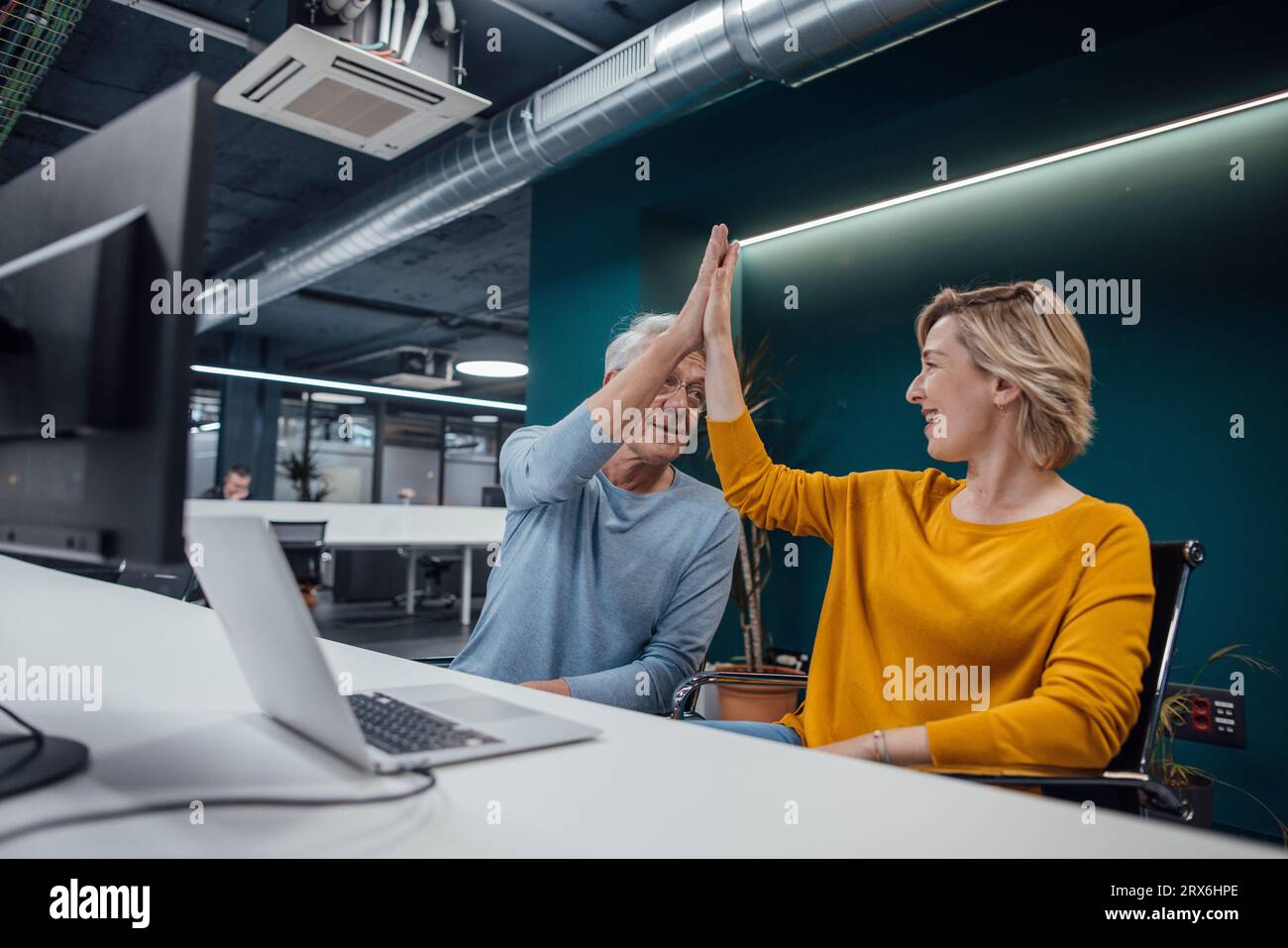 Collègues d'affaires qui se donnent cinq points forts les uns aux autres au bureau dans le bureau Banque D'Images
