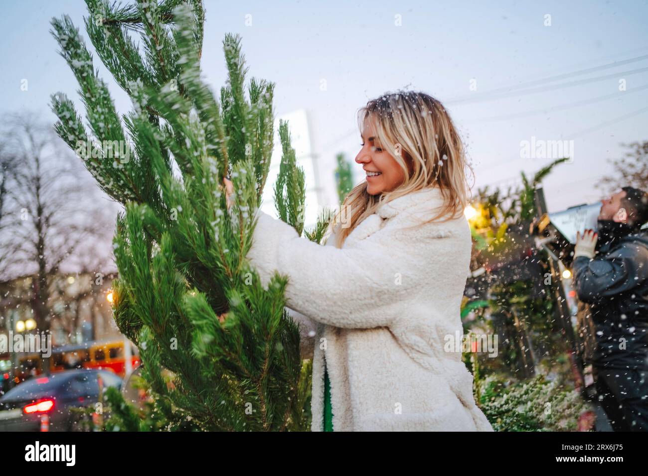 Femme souriante touchant l'arbre de Noël au marché Banque D'Images