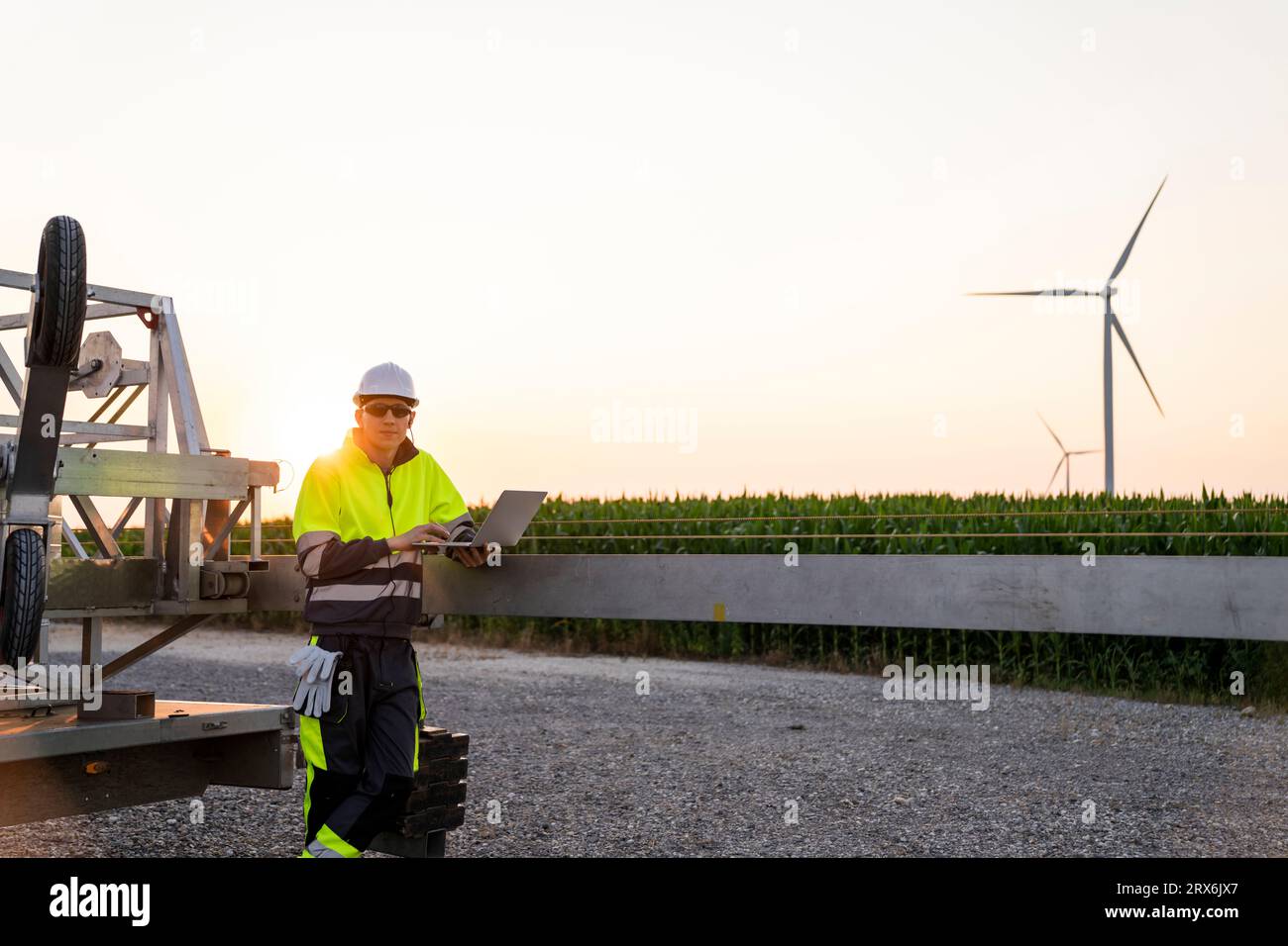 Ingénieur avec ordinateur portable près du parc d'éoliennes devant le ciel clair Banque D'Images