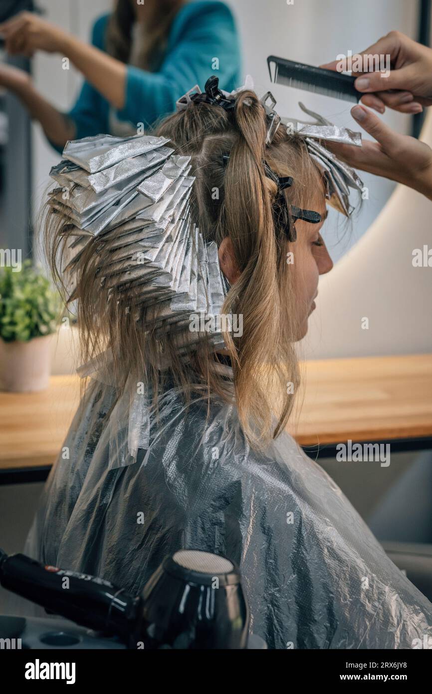 Coiffeur peignant les cheveux du client au salon Banque D'Images
