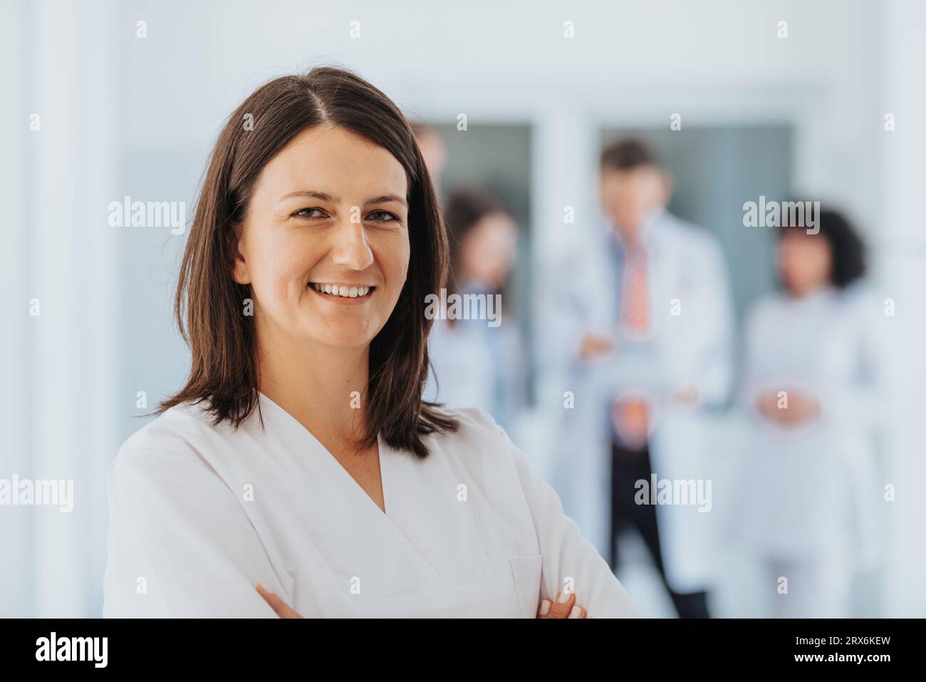 Médecin satisfaite et confiante en clinique, posant avec les bras pliés, portant une blouse de laboratoire. Spécialiste professionnel et performant fournissant des soins de santé s Banque D'Images