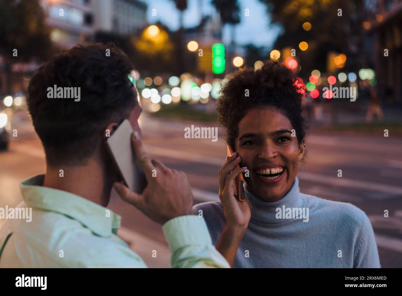 Femme et homme heureux parlant sur les téléphones intelligents Banque D'Images