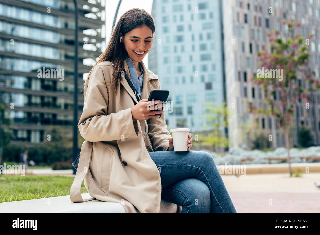 Femme heureuse utilisant le téléphone portable devant les bâtiments Banque D'Images
