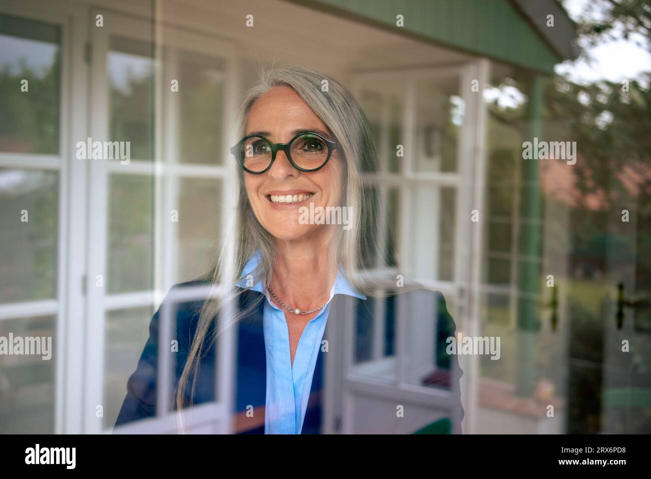 Femme d'affaires heureuse avec les cheveux gris vu à travers le verre Banque D'Images