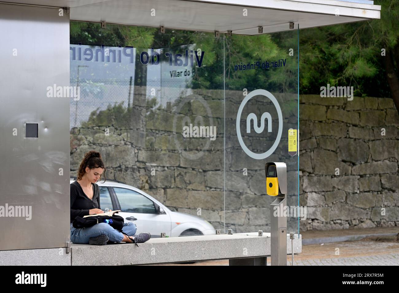Jolie jeune femme assise en attendant le train à la station de métro locale Porto, Portugal Banque D'Images