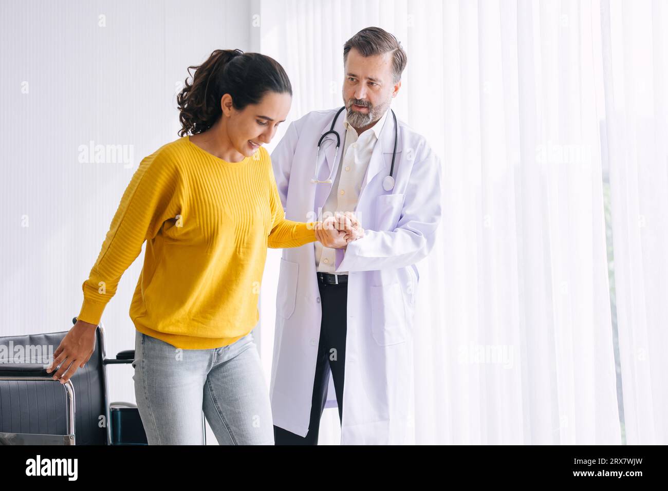 Femme blessure à la jambe médecin de physiothérapie aider à soutenir essayer de marcher et elle est très heureuse après la guérison et la récupération Banque D'Images