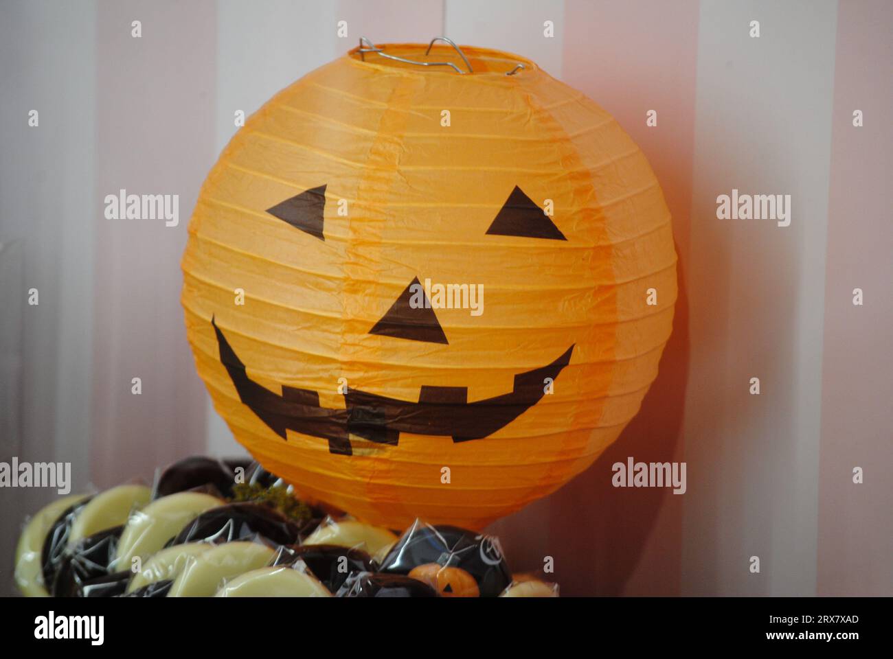 Lanterne en papier avec forme de citrouille souriante et chocolats montrant des idées d'Halloween Banque D'Images