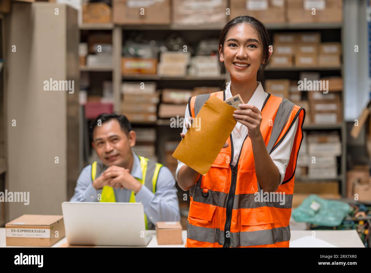 Jeune femme d'entrepôt travailleuse heureuse avec l'argent de bonus en espèces de salaire de travailler dur dans l'industrie de l'inventaire Banque D'Images