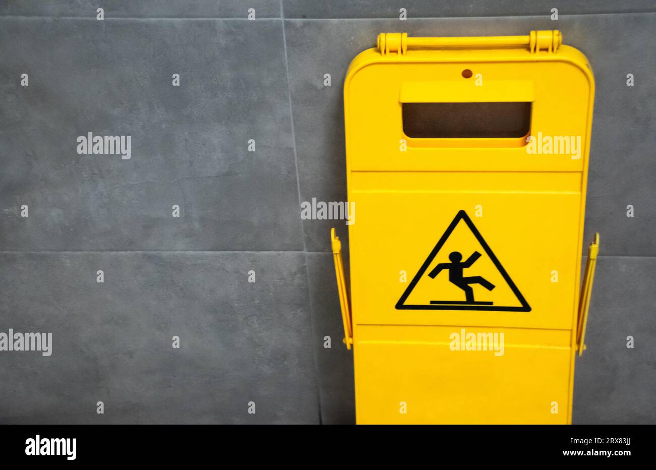 Image du signe jaune de plancher mouillé dans le plastique à l'intérieur de la salle de bain avec fond de carrelage bleu Banque D'Images