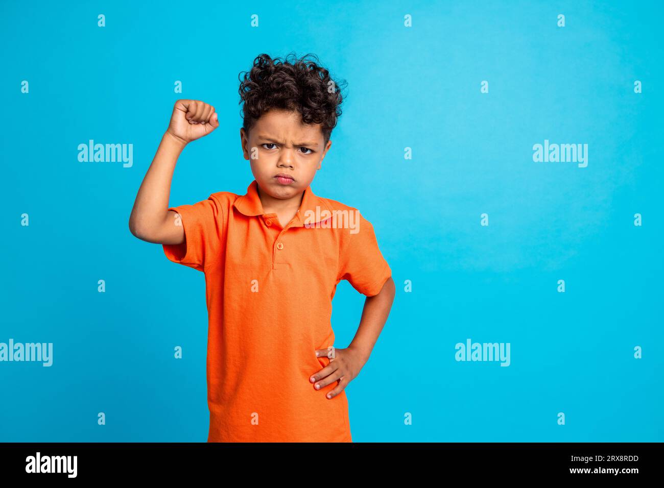 Photo de garçon frustré soulever le poing up lutte pour les droits humains des enfants isolés sur fond de couleur bleue Banque D'Images