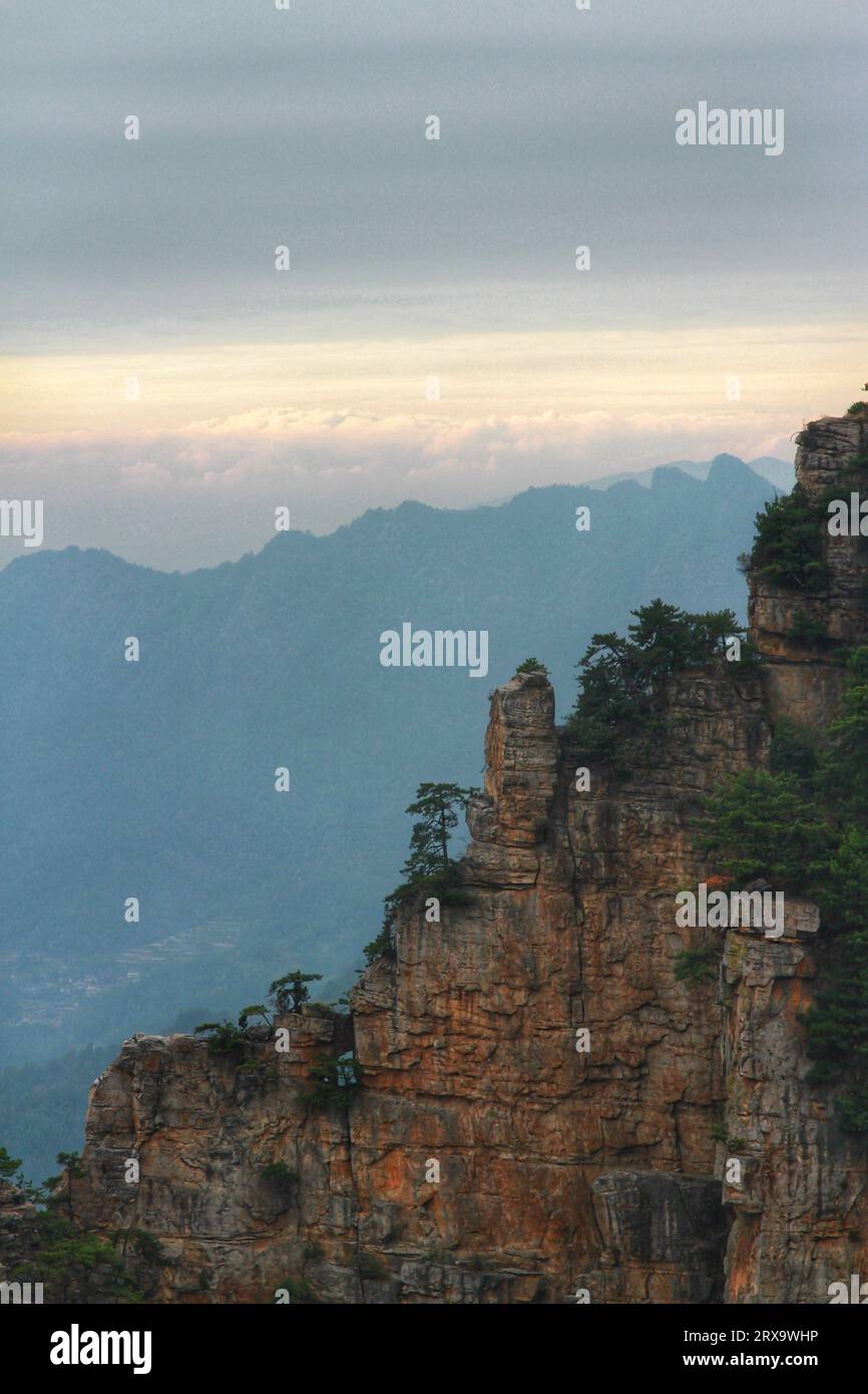 Capturez la beauté à couper le souffle d'une nature verdoyante nichée dans l'étreinte de montagnes imposantes sous un ciel nuageux Banque D'Images