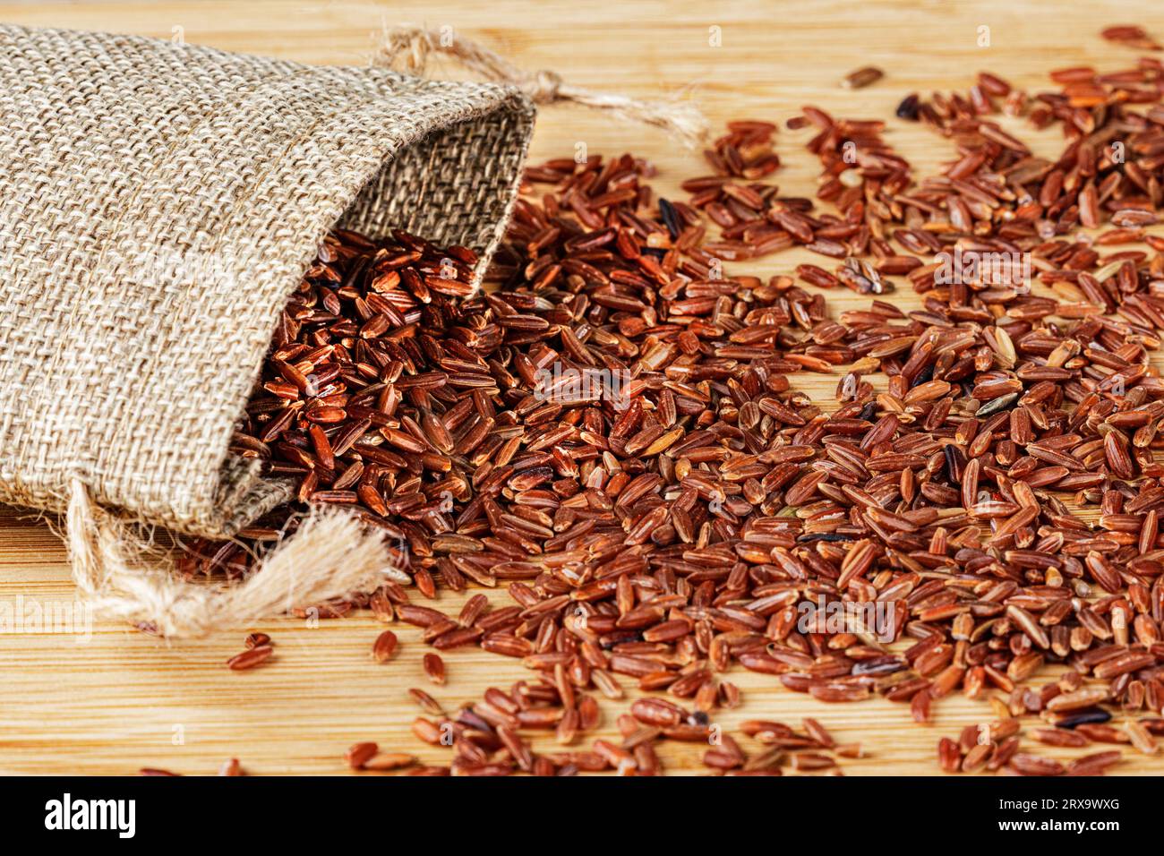 Un sac de Burlap ou sac de Burlap de riz rouge délicieux et sain isolé sur un fond en bois avec espace de copie Banque D'Images