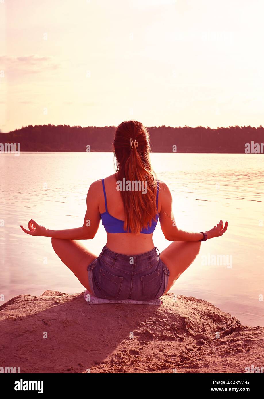 Adorable jeune femme est assise sur la jetée sur le beau lac de montagne et médite. Style de vie. Banque D'Images