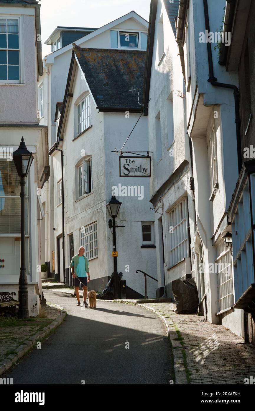 Homme marchant Un chien sur Smith Street avec des bâtiments historiques, Dartmouth, Royaume-Uni Banque D'Images