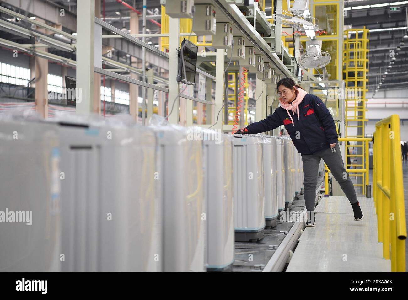 Xi'an, province chinoise du Shaanxi. 22 février 2023. Un employé assemble des machines à laver sur une ligne de production d'une entreprise d'appareils électriques près du port international de Xi'an à Xi'an, dans la province du Shaanxi au nord-ouest de la Chine, le 22 février 2023. Le service de train de marchandises Chine-Europe de Chang'an a été lancé en 2013, lorsque la Chine a proposé l'initiative Belt and Road. Au cours des dix dernières années, le port international de Xi'an, la station de départ des trains de fret Chang'an Chine-Europe, a été développé d'une petite station de fret à un centre logistique international. Crédit : Shao Rui/Xinhua/Alamy Live News Banque D'Images