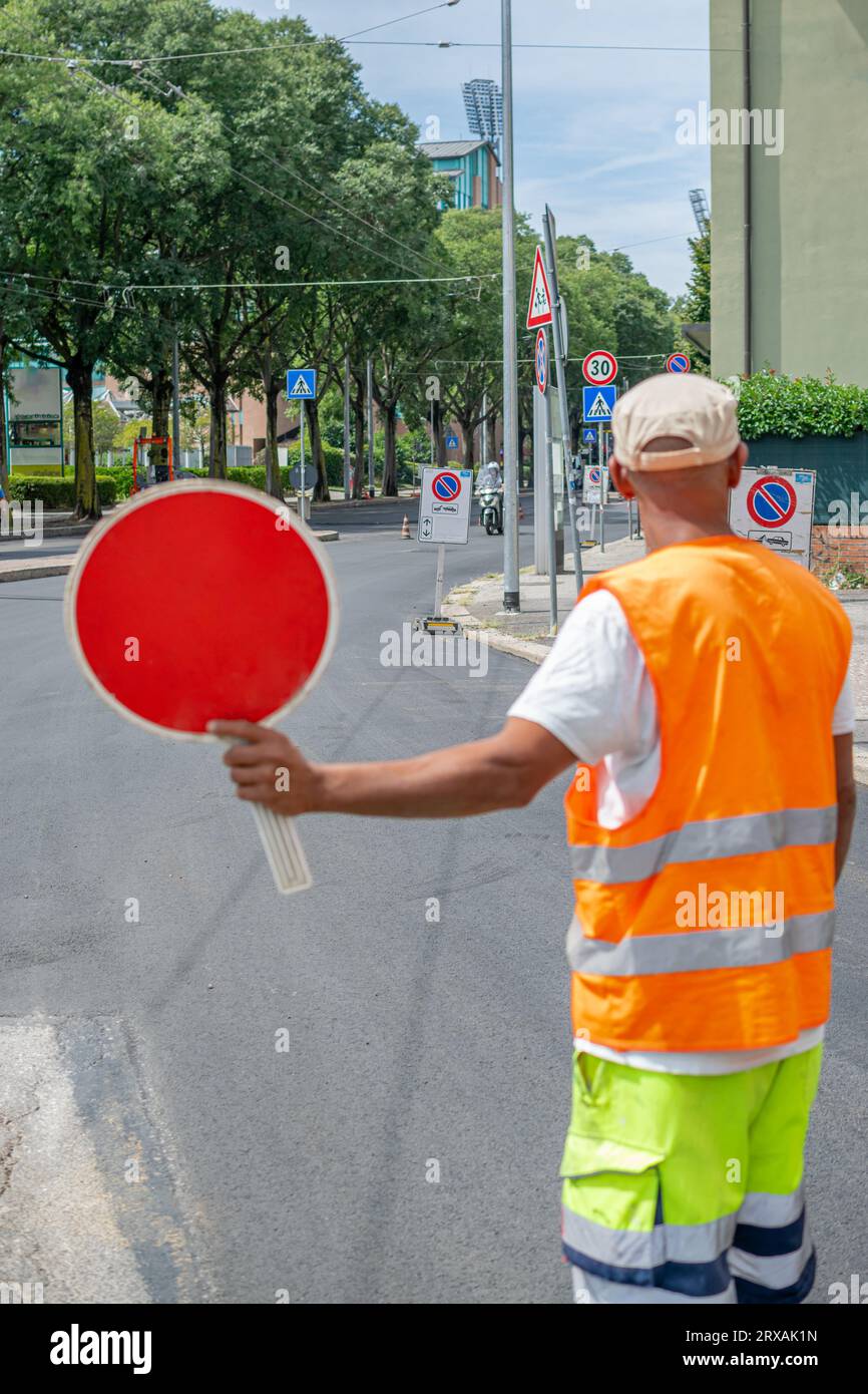 Travailleur de la construction tenant un panneau d'arrêt rouge et dirigeant la circulation dans la rue Banque D'Images