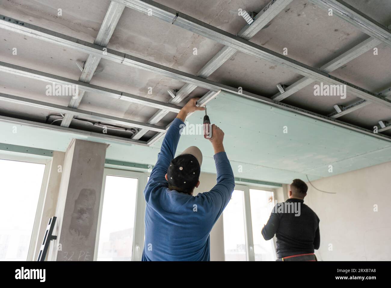 Installation au plafond avec des techniciens experts dans la pièce en cours de construction Banque D'Images