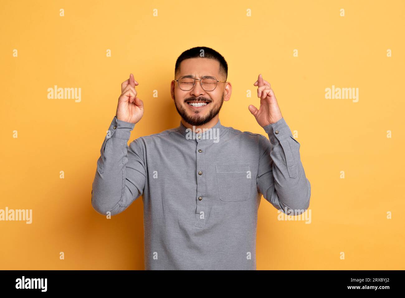 Faire vœu. Portrait de Jeune homme asiatique joyeux gardant les doigts croisés Banque D'Images