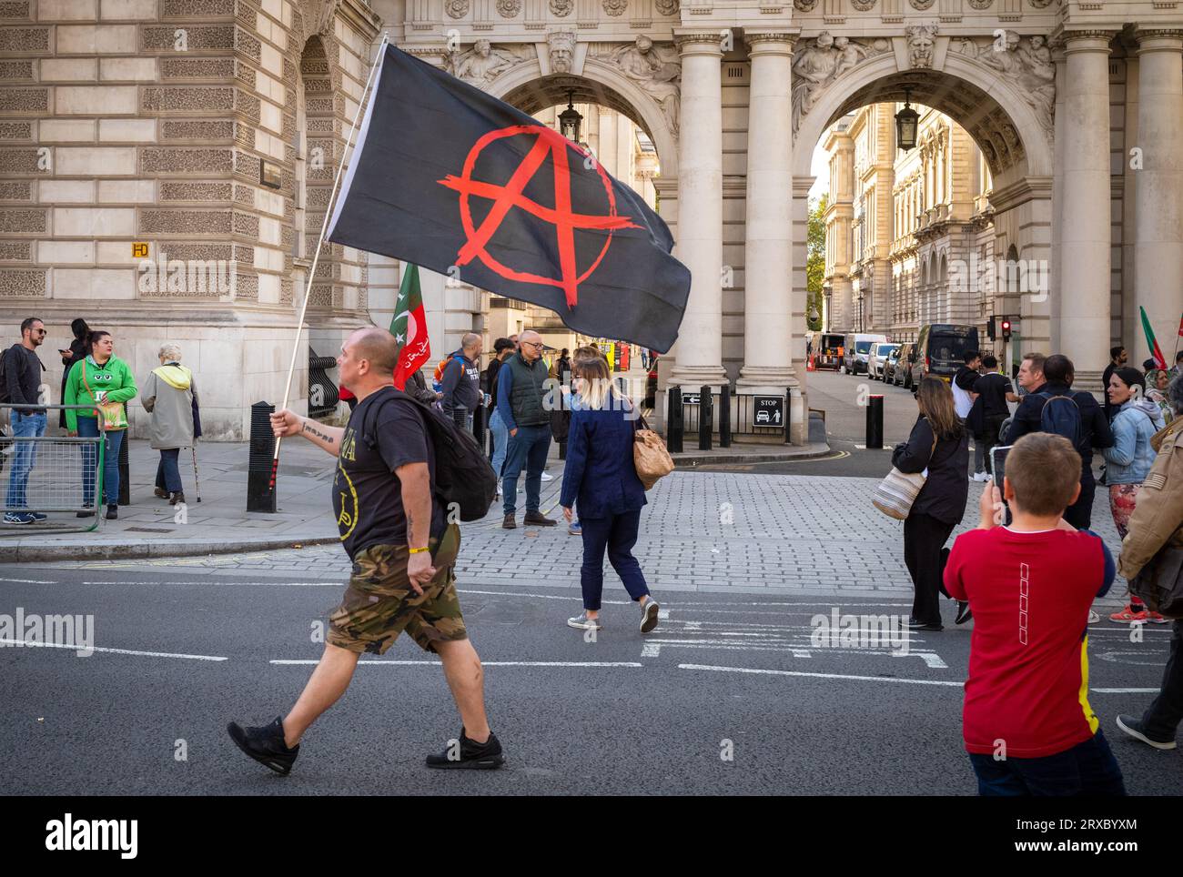 Un homme porte un drapeau anarchiste devant le ministère britannique des Affaires étrangères et les touristes alors qu'il descend Whitehall dans le centre de Londres. Il avait été atte Banque D'Images