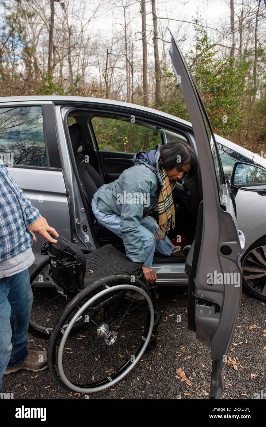 Un couplearrive outdoorsy dans un camping accessible aux handicapés. La femme passe de la voiture à son fauteuil roulant. Les deux sont handicapés mais adorent le ou Banque D'Images