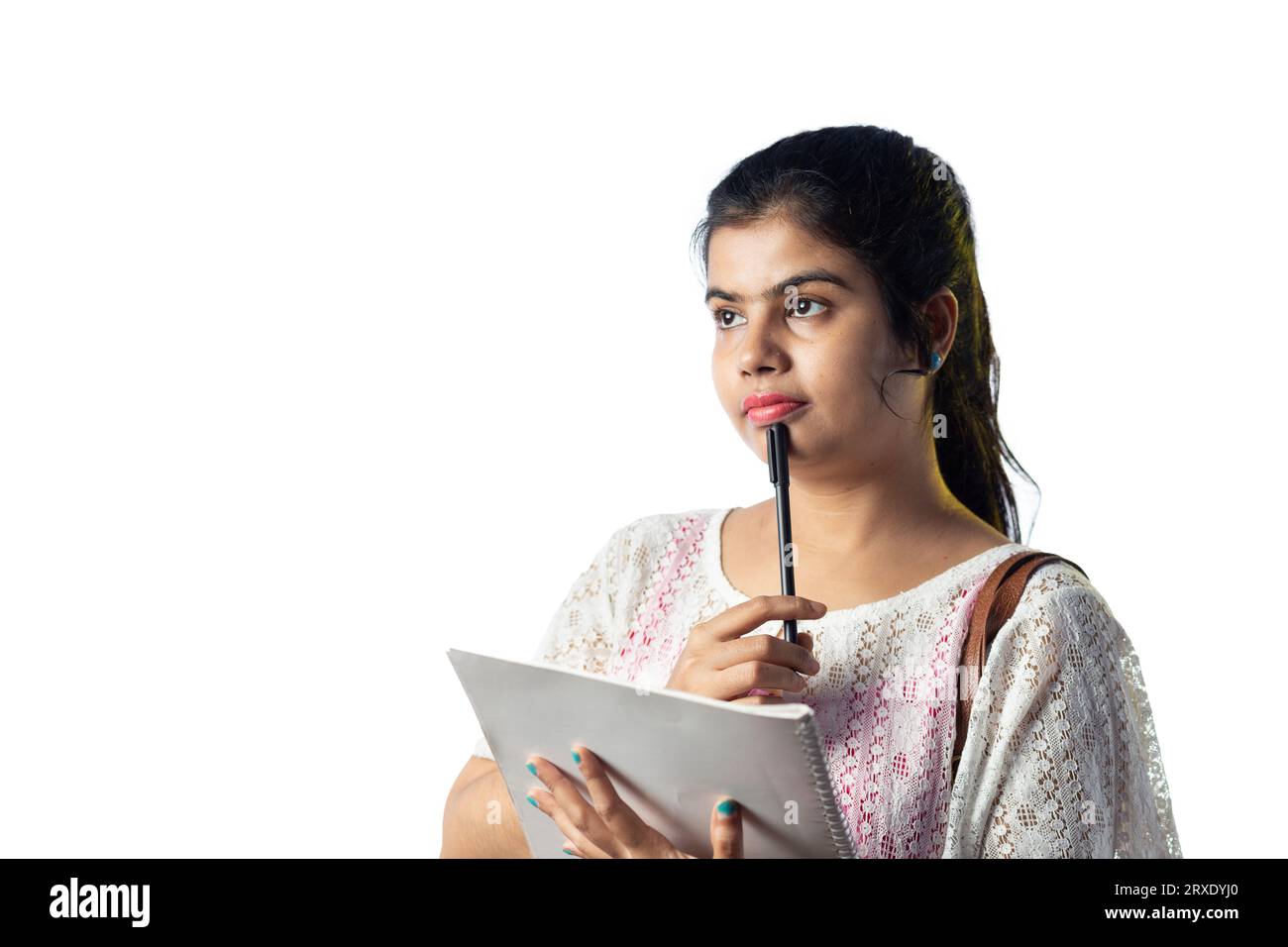 Une jolie jeune fille indienne pensant tout en prenant des notes et regardant de côté sur fond blanc Banque D'Images