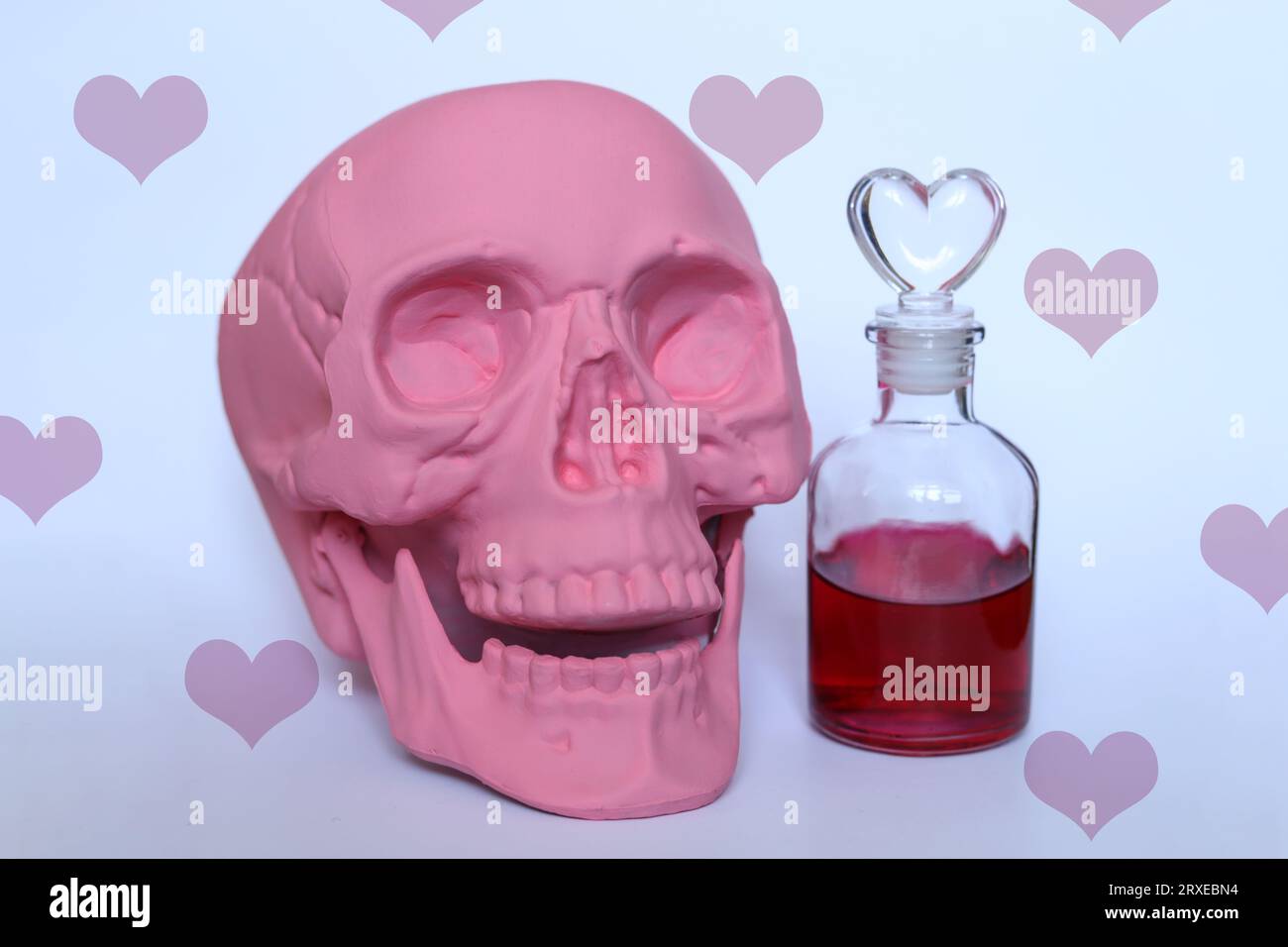 nature morte avec un crâne rose pastel et potion d'amour avec un fond de motif coeurs Banque D'Images