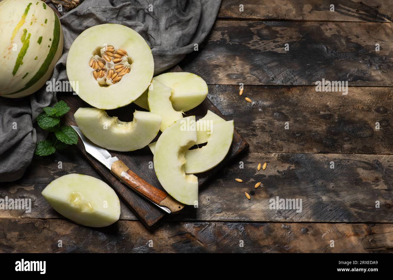 Melon gaya ivoire avec des rayures pointillées vertes et des taches sur un fond en bois. Fruits mûrs colorés, juteux et mous, goût sucré avec des notes florales. Entier Banque D'Images