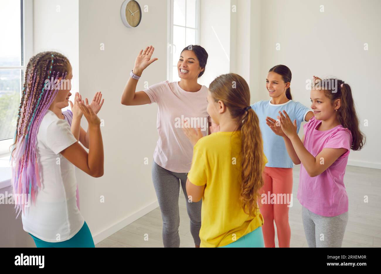 Chorégraphe sympathique féminin donnant High Five à ses élèves filles dans le studio de danse. Banque D'Images