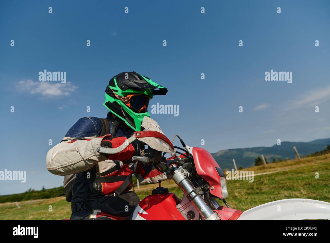 Un coureur de motocross professionnel, entièrement équipé avec casque, gants et lunettes, assis sur sa moto, prêt à embarquer pour une aventure palpitante Banque D'Images