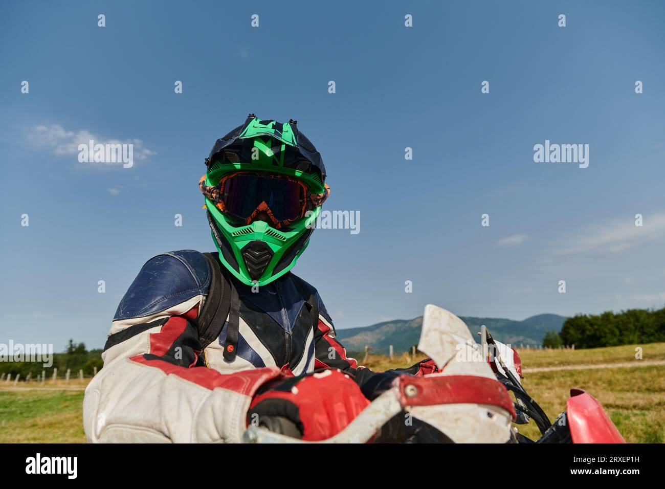 Un coureur de motocross professionnel, entièrement équipé avec casque, gants et lunettes, assis sur sa moto, prêt à embarquer pour une aventure palpitante Banque D'Images