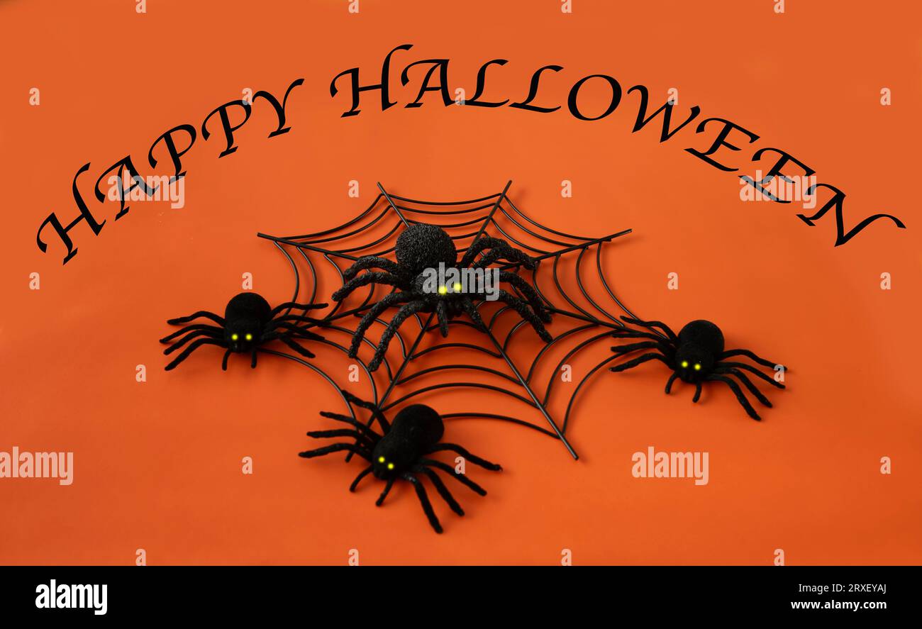 Signe joyeux Halloween avec des araignées sur un fond orange. Banque D'Images