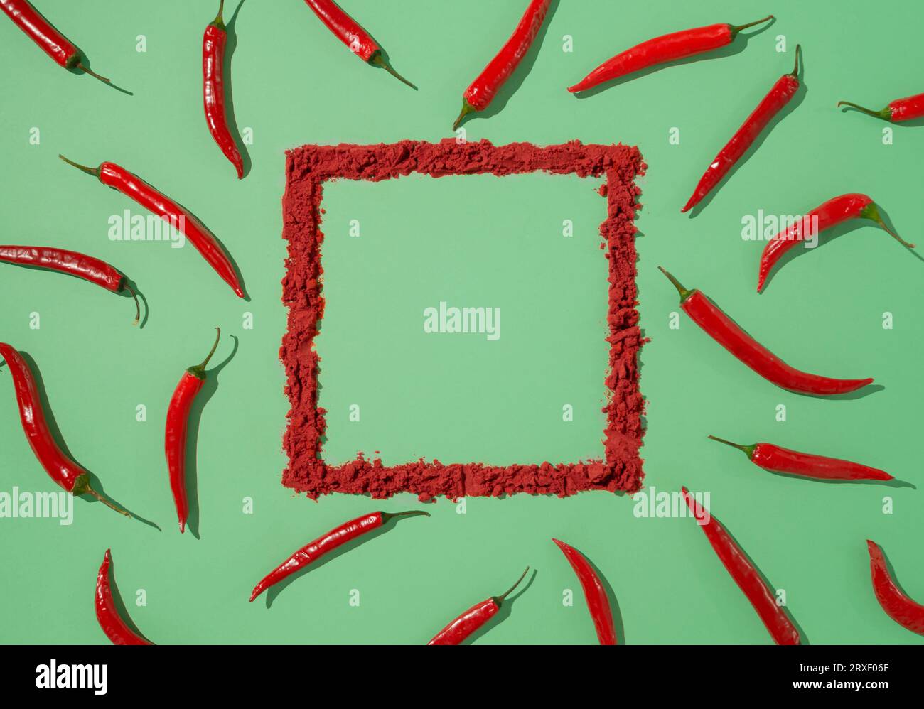 Motif créatif fait de piments piments rouges sur fond vert pastel avec cadre naturel. Pose à plat minimale. Banque D'Images