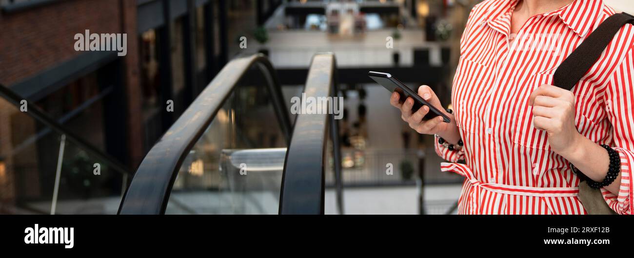 Une femme tient un téléphone portable dans un centre commercial. Banque D'Images