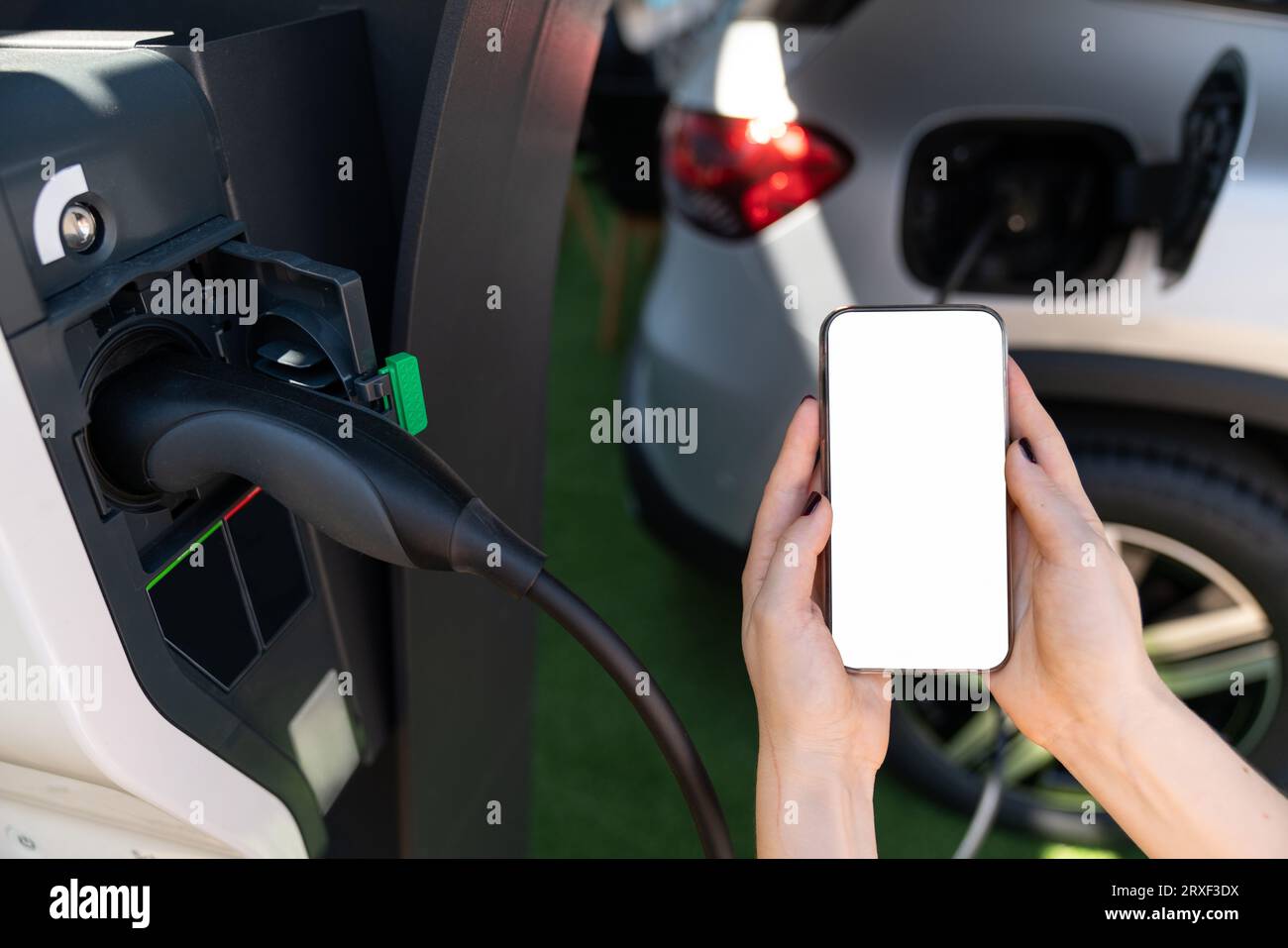 Mains avec smartphone et prise de charge sur un fond de voiture électrique. Ecran blanc, vous pouvez ajouter votre contenu ici. Banque D'Images