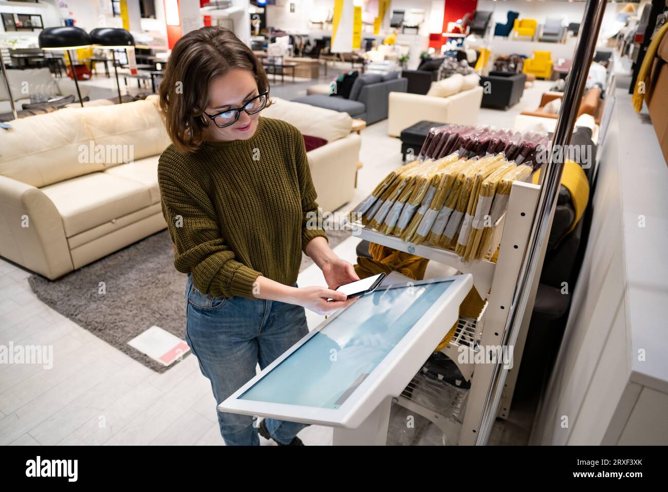 Femme avec le téléphone utilise le kiosque libre-service dans le centre commercial. Banque D'Images