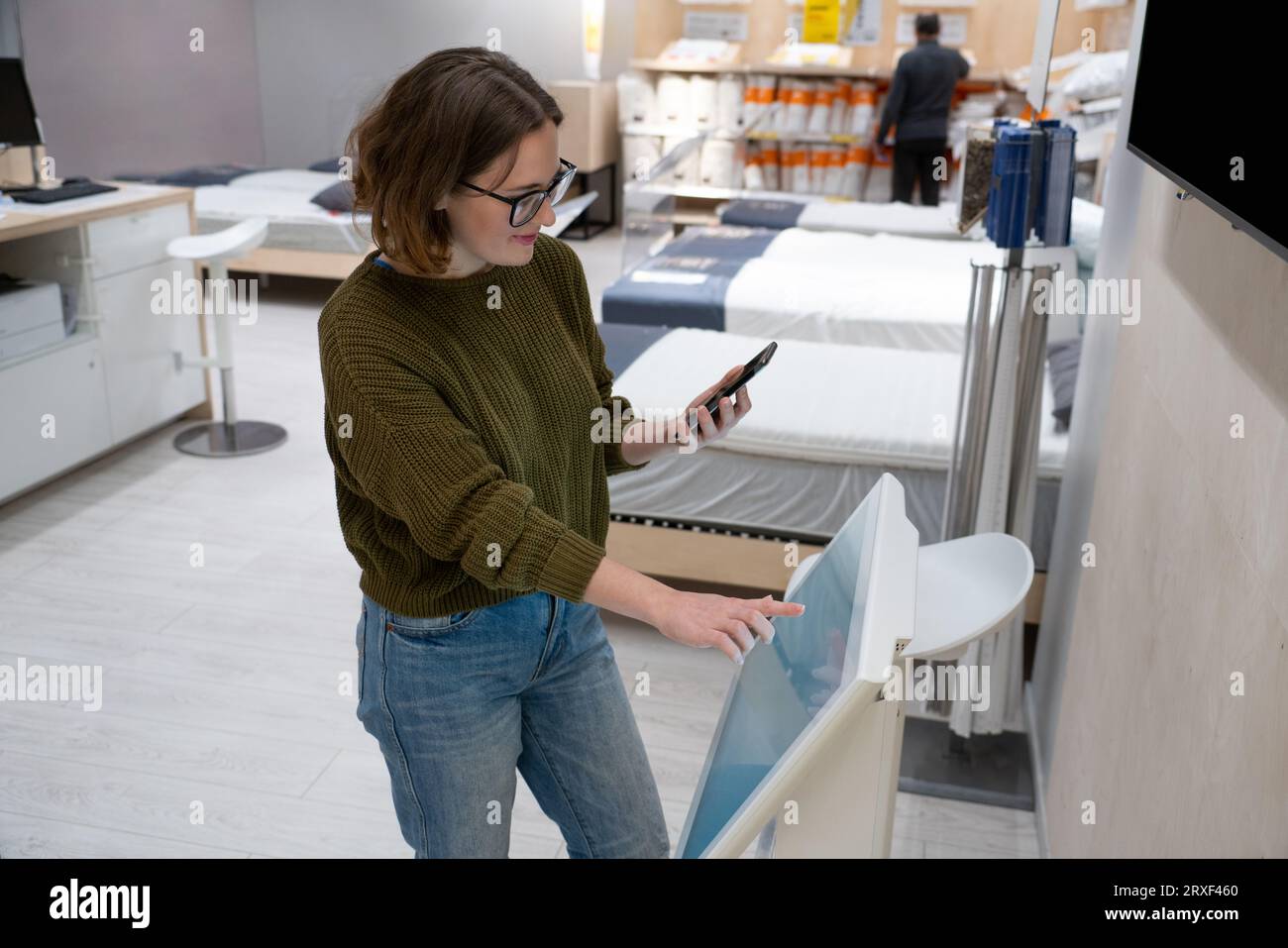Femme avec le téléphone utilise le kiosque libre-service dans le centre commercial. Banque D'Images