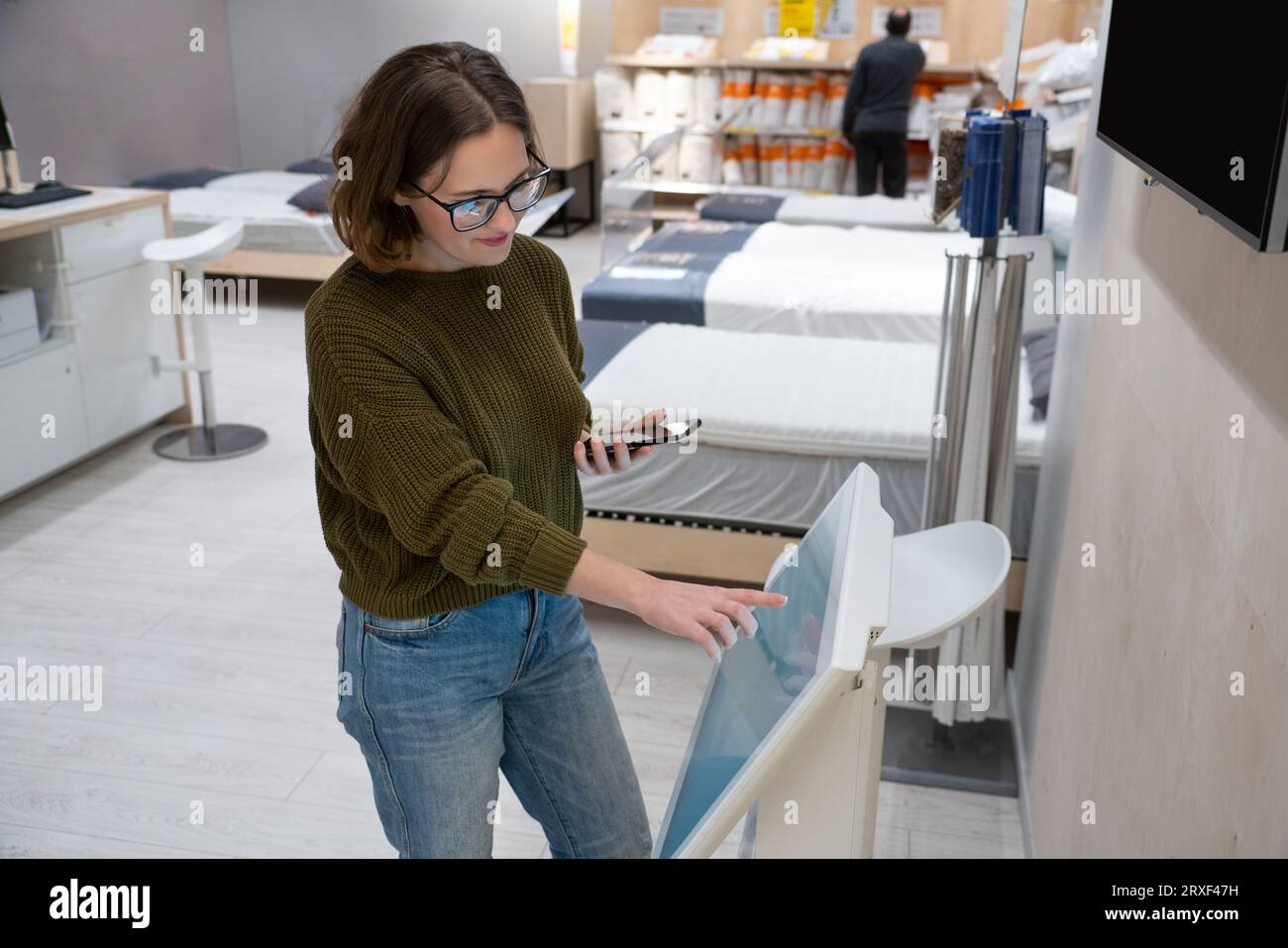 Femme avec le téléphone utilise le kiosque libre-service dans le centre commercial. Banque D'Images
