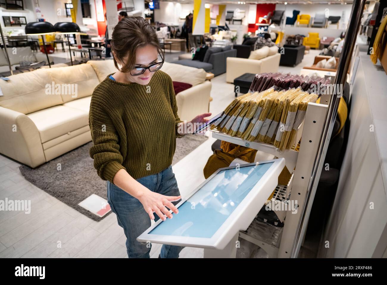 Femme avec le téléphone utilise le kiosque libre-service dans le centre commercial. Banque D'Images