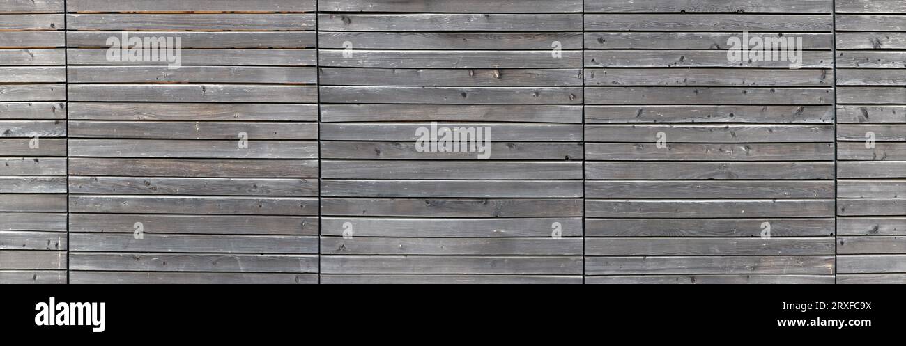 Clôture en bois orange vif inondée de lumière du soleil. Un bloc de panneaux de bois horizontaux avec des noeuds. Pour les arrière-plans et textures en bois abstraits. Banque D'Images