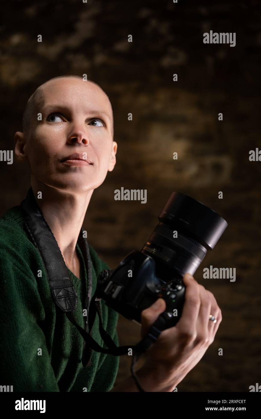 Une passionnée de photographie, une femme dans sa prime, tenant un appareil photo et capturant des sourires avec un fond sombre Banque D'Images