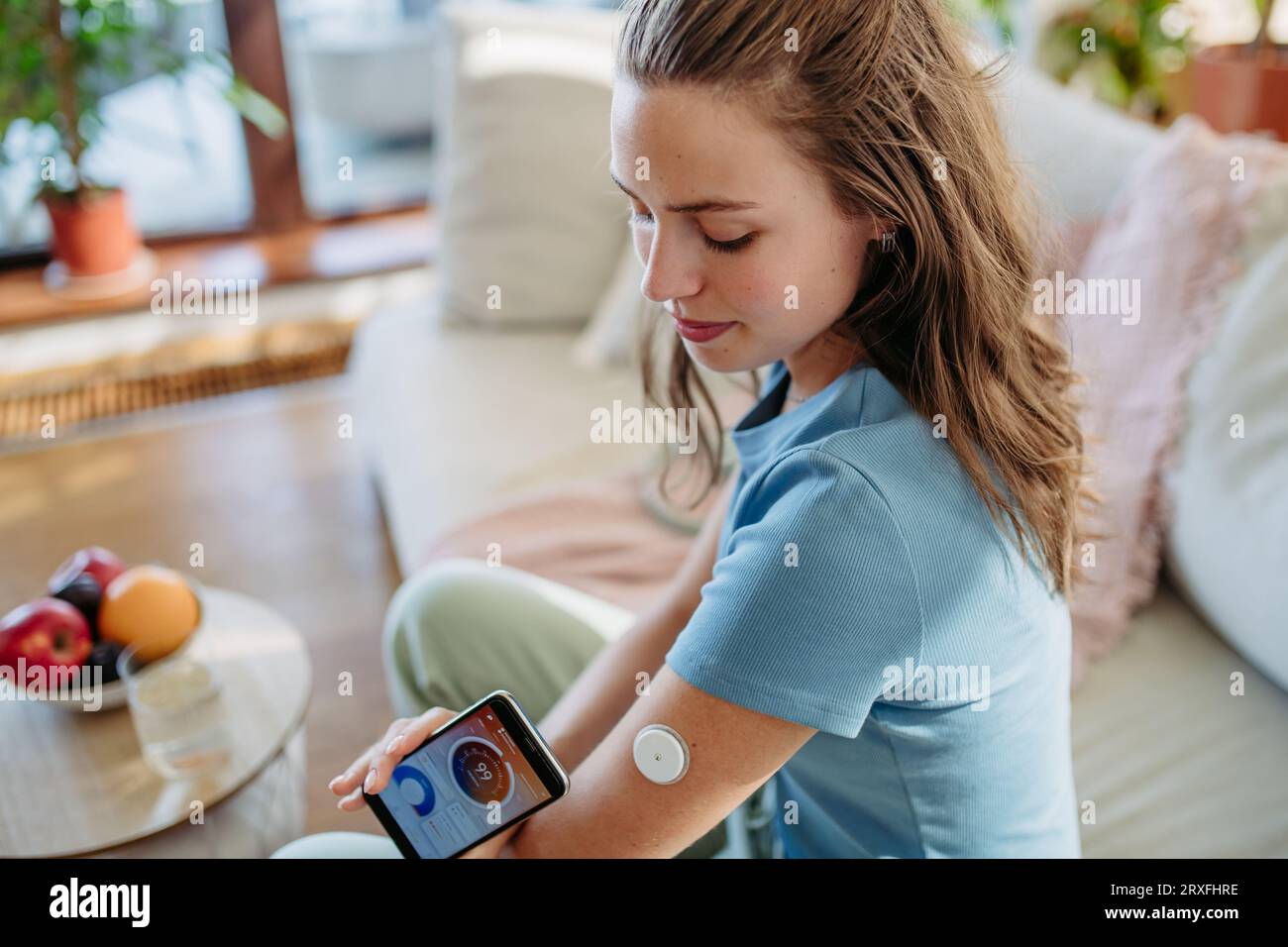 Femme diabétique vérifiant le taux de glucose sanguin à la maison à l'aide d'un moniteur de glucose continu. Banque D'Images