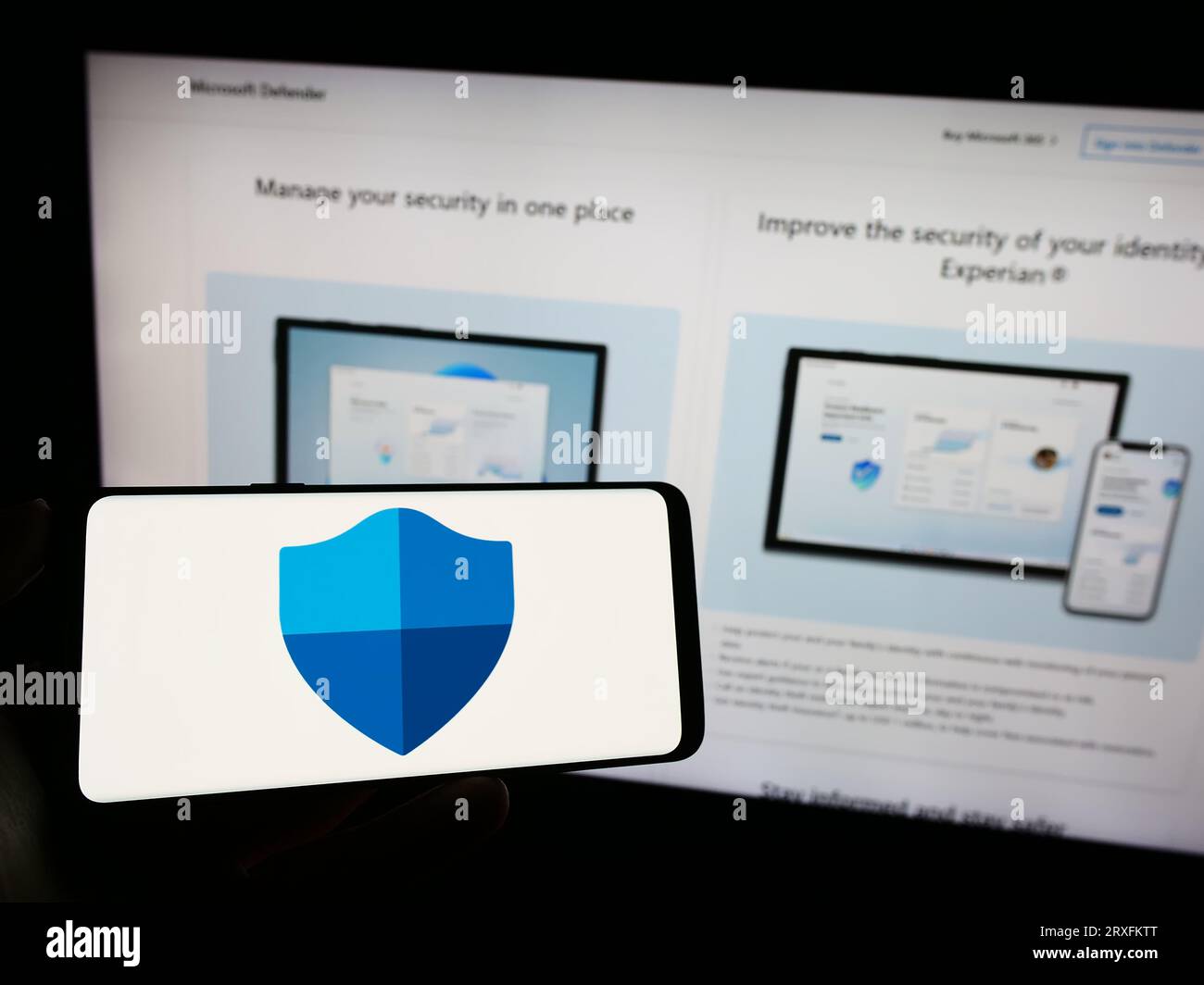Personne tenant le téléphone portable avec le logo du logiciel de sécurité Microsoft Defender antivirus sur l'écran en face de la page Web. Concentrez-vous sur l'affichage du téléphone. Banque D'Images