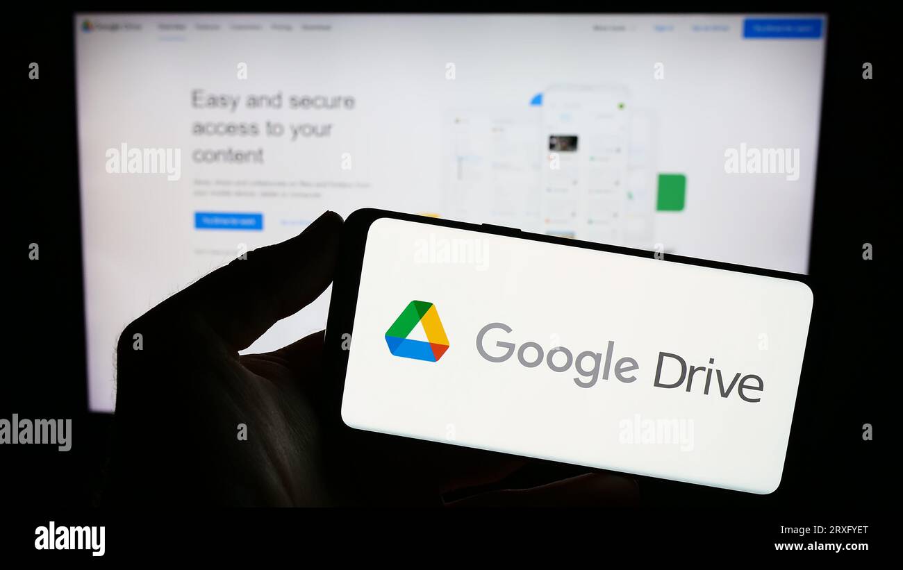 Personne tenant smartphone avec logo de la plate-forme de stockage de fichiers Google Drive sur l'écran en face du site Web. Concentrez-vous sur l'affichage du téléphone. Banque D'Images