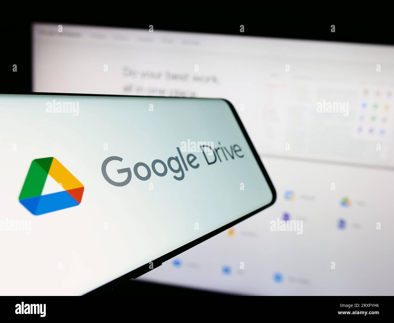 Téléphone mobile avec logo de la plate-forme de stockage de fichiers Google Drive sur l'écran en face du site Web de l'entreprise. Concentrez-vous sur le centre gauche de l'écran du téléphone. Banque D'Images