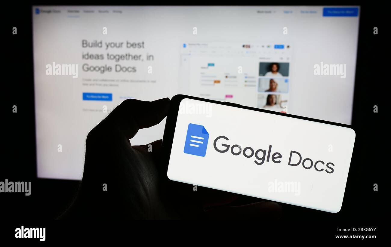Personne tenant le téléphone mobile avec le logo du produit de traitement de texte en ligne Google Docs sur l'écran en face de la page Web. Concentrez-vous sur l'affichage du téléphone. Banque D'Images