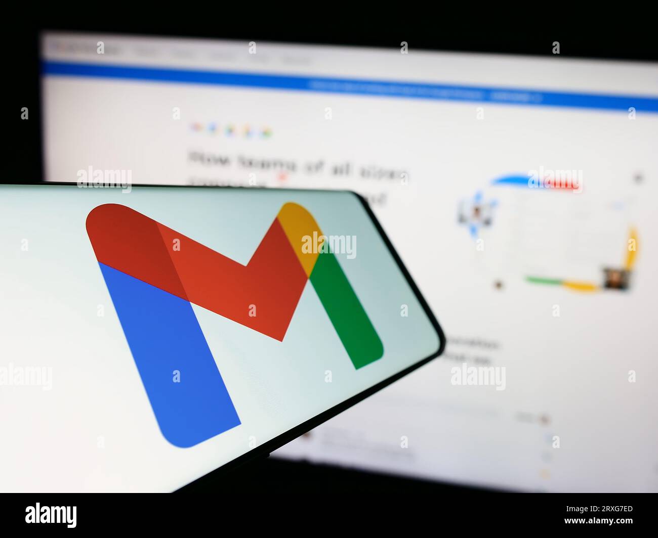 Smartphone avec logo du service de messagerie Google Gmail sur l'écran en face du site Web de l'entreprise. Concentrez-vous sur le centre gauche de l'écran du téléphone. Banque D'Images